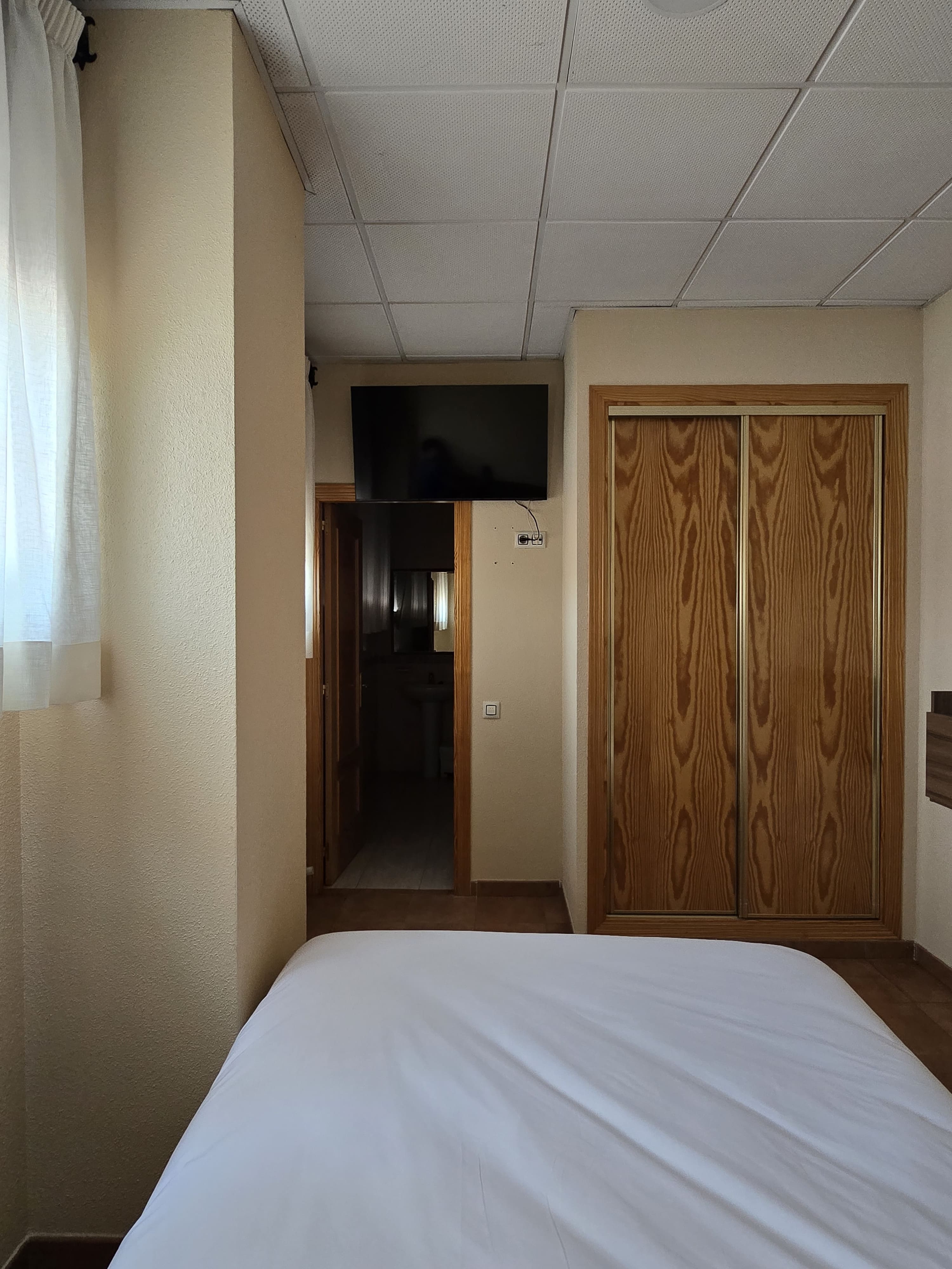 Cama matrimonial con cabecero de lamas en habitación individual